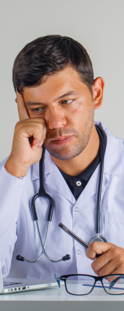 doctor-white-coat-stethoscope-sitting-looking-laptop-looking-careful